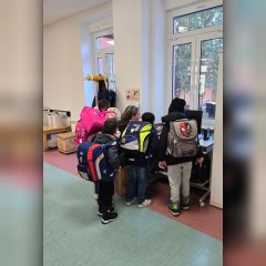 Kinder stehen mit Mitarbeitenden am PC