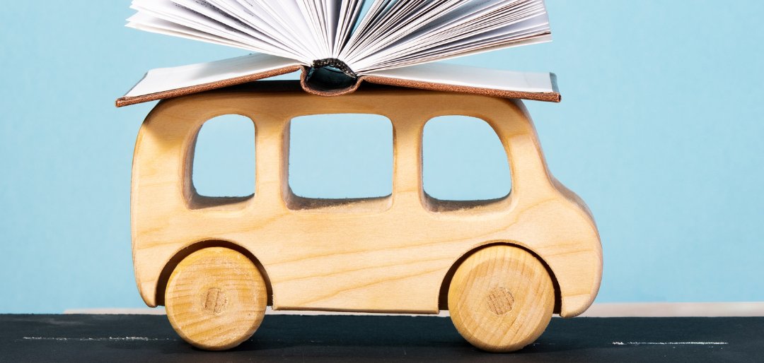 Holzauto mit aufgeschlagenem Buch auf dem Dach