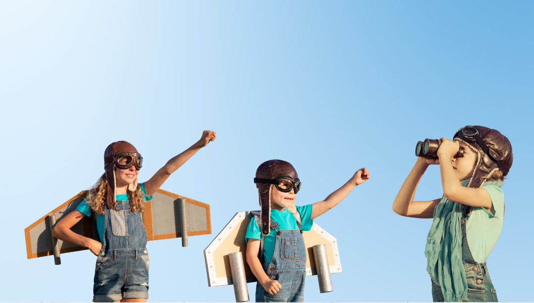 Kinder sind verkleidet mit Pilotenbrille über den Augen uns selbstgebastelten Flügeln aus Karton auf dem Rücken.