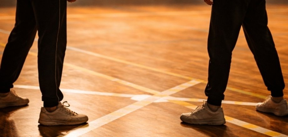 Zwei Kinder stehen sich in einer Turnhalle gegenüber