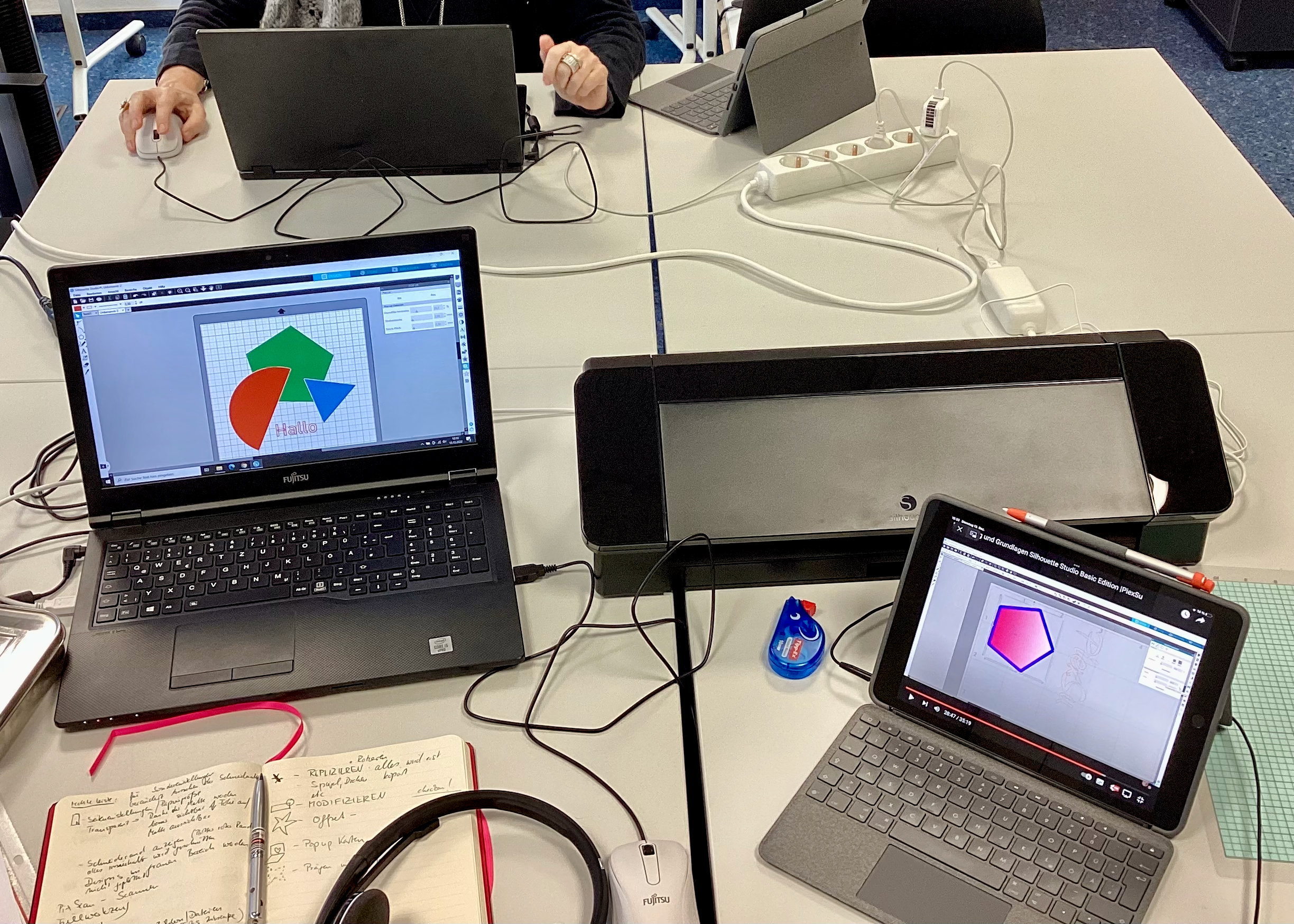Plotten für Fortgeschrittene Ein Plotter, ein PC und ein Tablet sind zu sehen. Der Bildschirm zeigt eine mehrfarbige Vorlage, die geplottet werden soll.