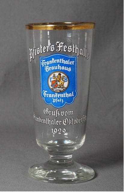 Bierglas mit der weißen Zier-Aufschrift "Pfister’s Festhalle. Gruß vom Frankenthaler Oktoberfest 1929“ und mittig dem damals aktuellen Logo des Frankenthaler Brauhauses, umgeben von der Schrift "Frankenthaler Brauhaus" (oben) und Frankenthal, Pfalz (unten) auf blauem Grund. Das Glas hat einen Goldrand. Logo des Brauhauses: Blauer Grund, mittig in Wappenform ein Löwe, der ein Wappen und einen Reichsapfel hält.