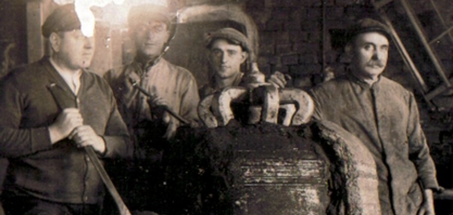 Szene in der Gießerei Hamm Szene in der Gießerei Hamm, vor dem Zweiten Weltkrieg: "Geburt" einer Glocke. Der Lehmmantel wird zerschlagen, die gegossene Glocke kommt zum Vorschein. Das Ereignis wurde fotografisch mit dem Team festgehalten.