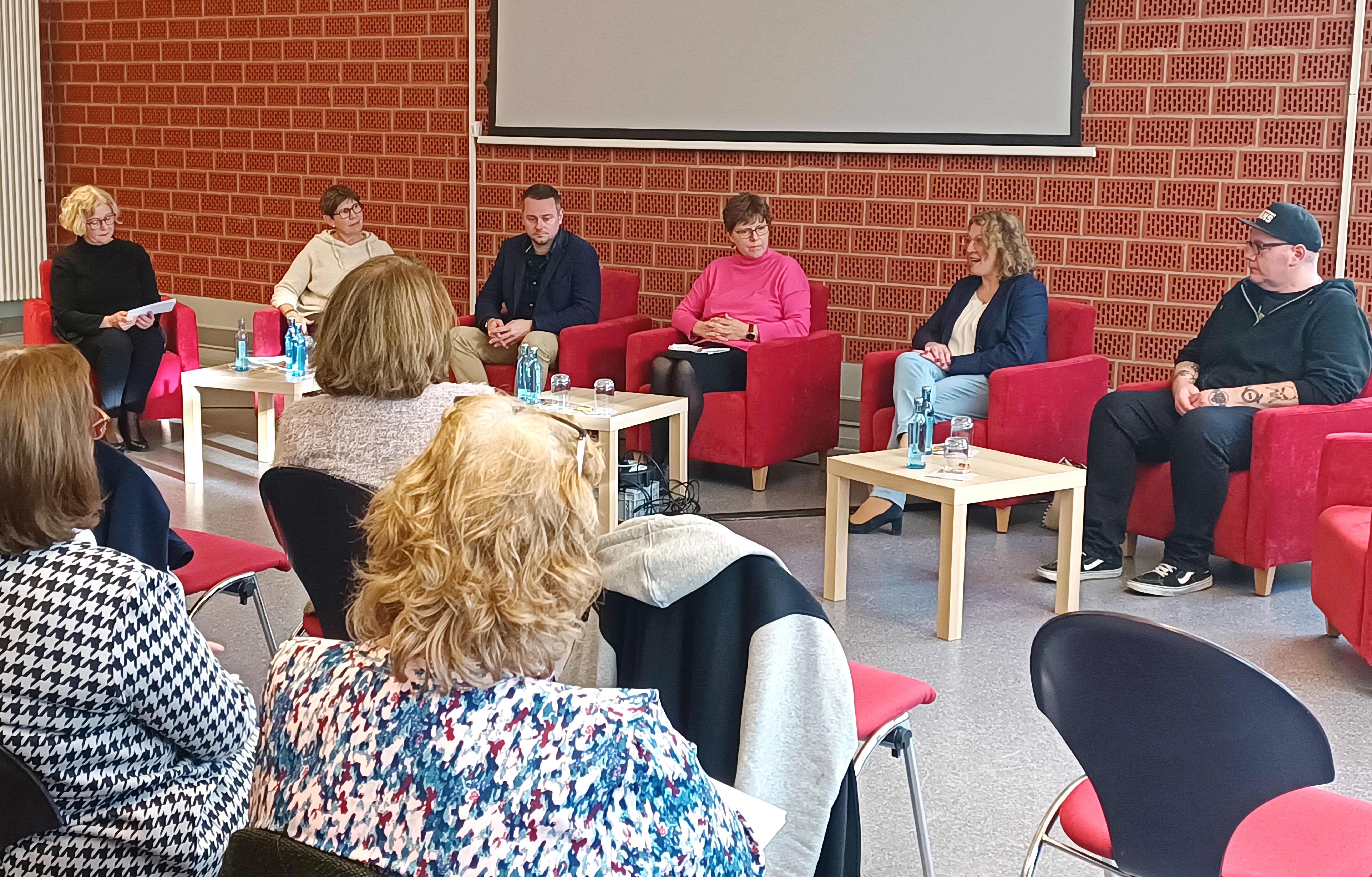 Auf dem Bild ist eine Talkrunde von Frauen und Männern sitzend zu sehen 