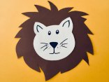Löwen-Rätsel in der Stadtbücherei Ein ausgeschnittenes Löwengesicht aus Papier liegt auf einem orangenen Hintergrund.