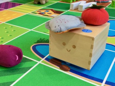 Medienaktionstag mit Cubetto-Roboter Ein kleiner Cubetto-Holzroboter auf einer bunten Aktionsfläche